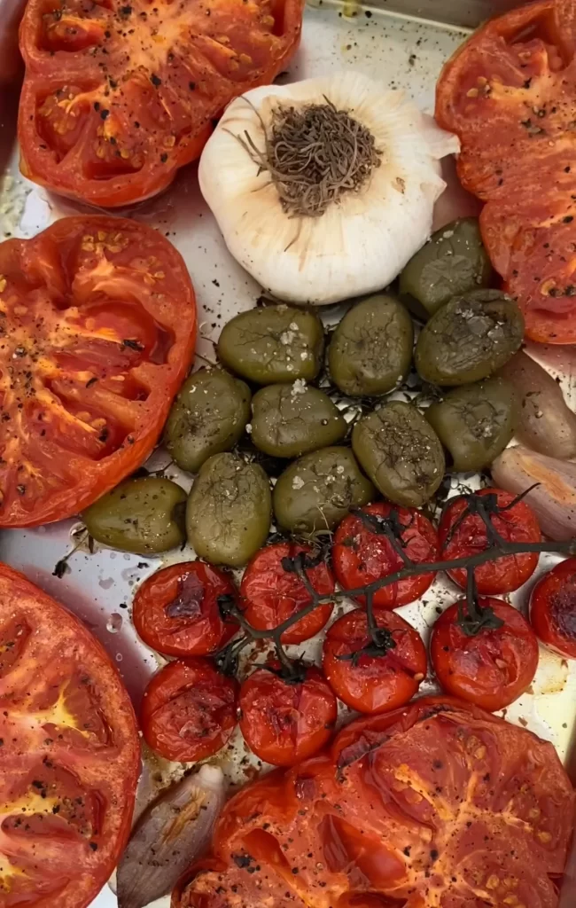 roasted olives, garlic, and tomatoes on a baking tray