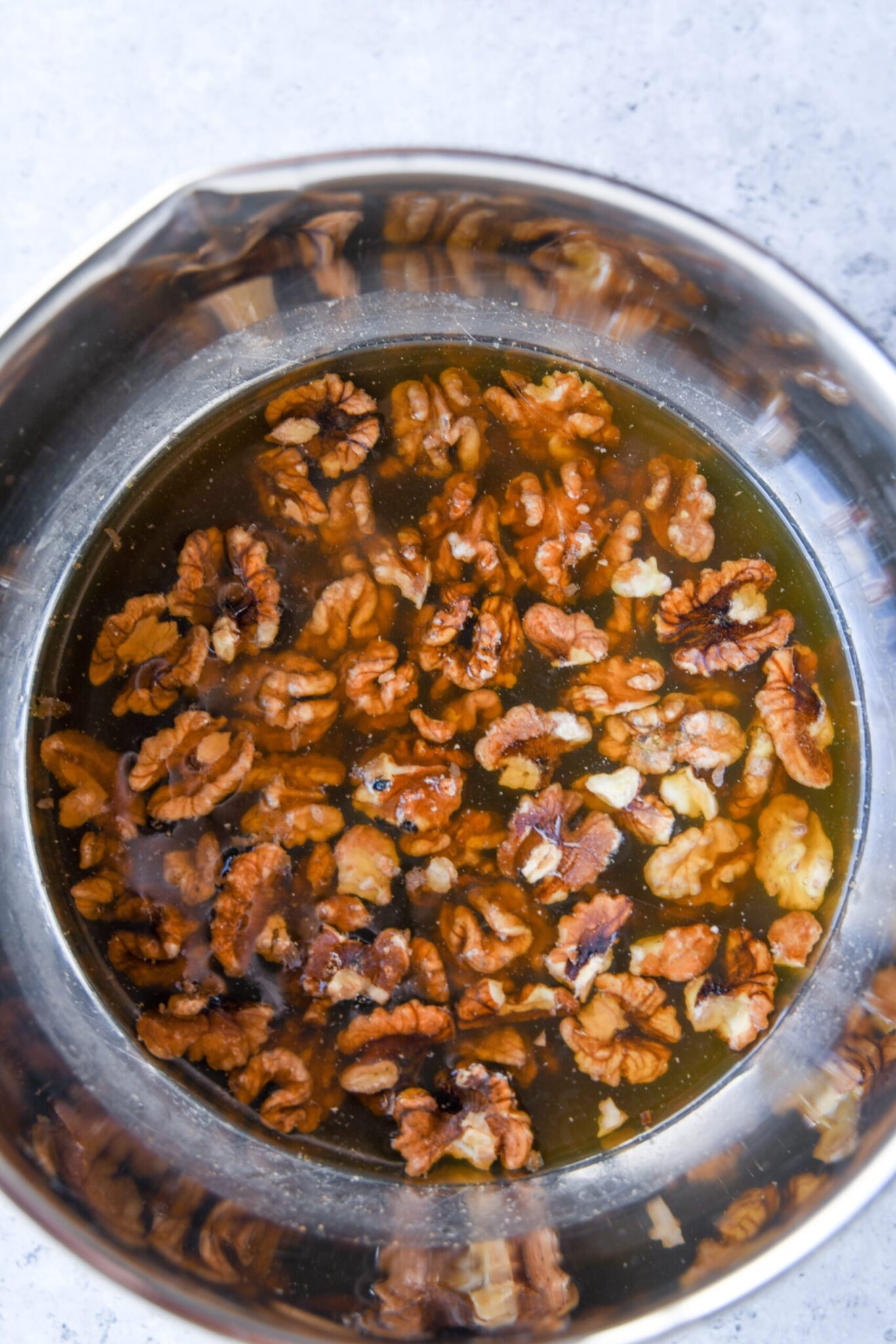 walnuts soaking in a metal bowl with water