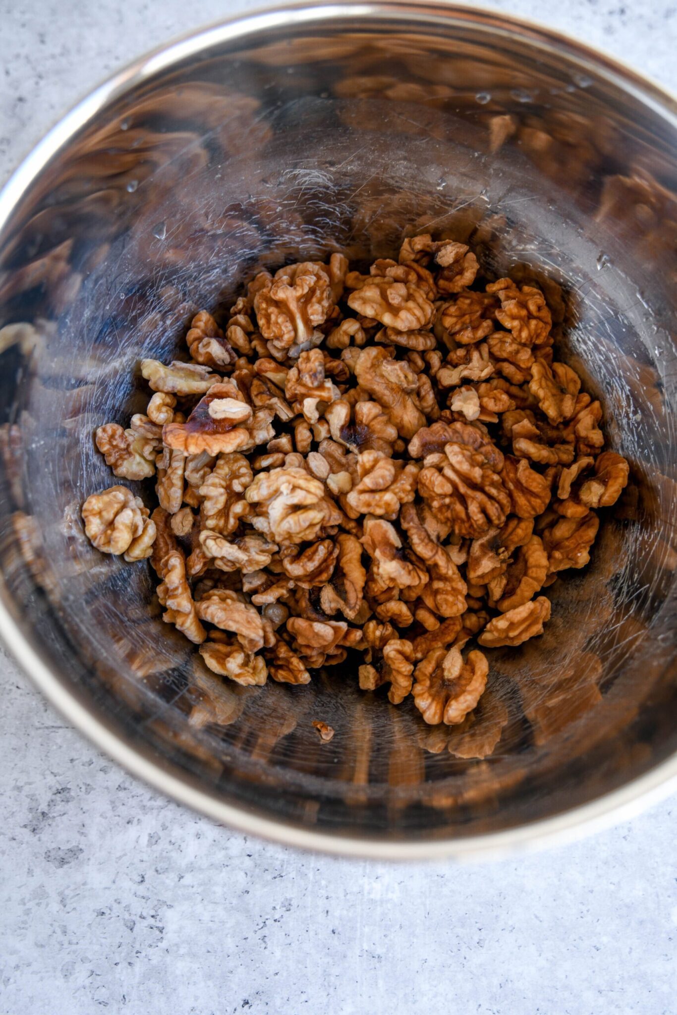 walnuts soaking in a metal bowl with water