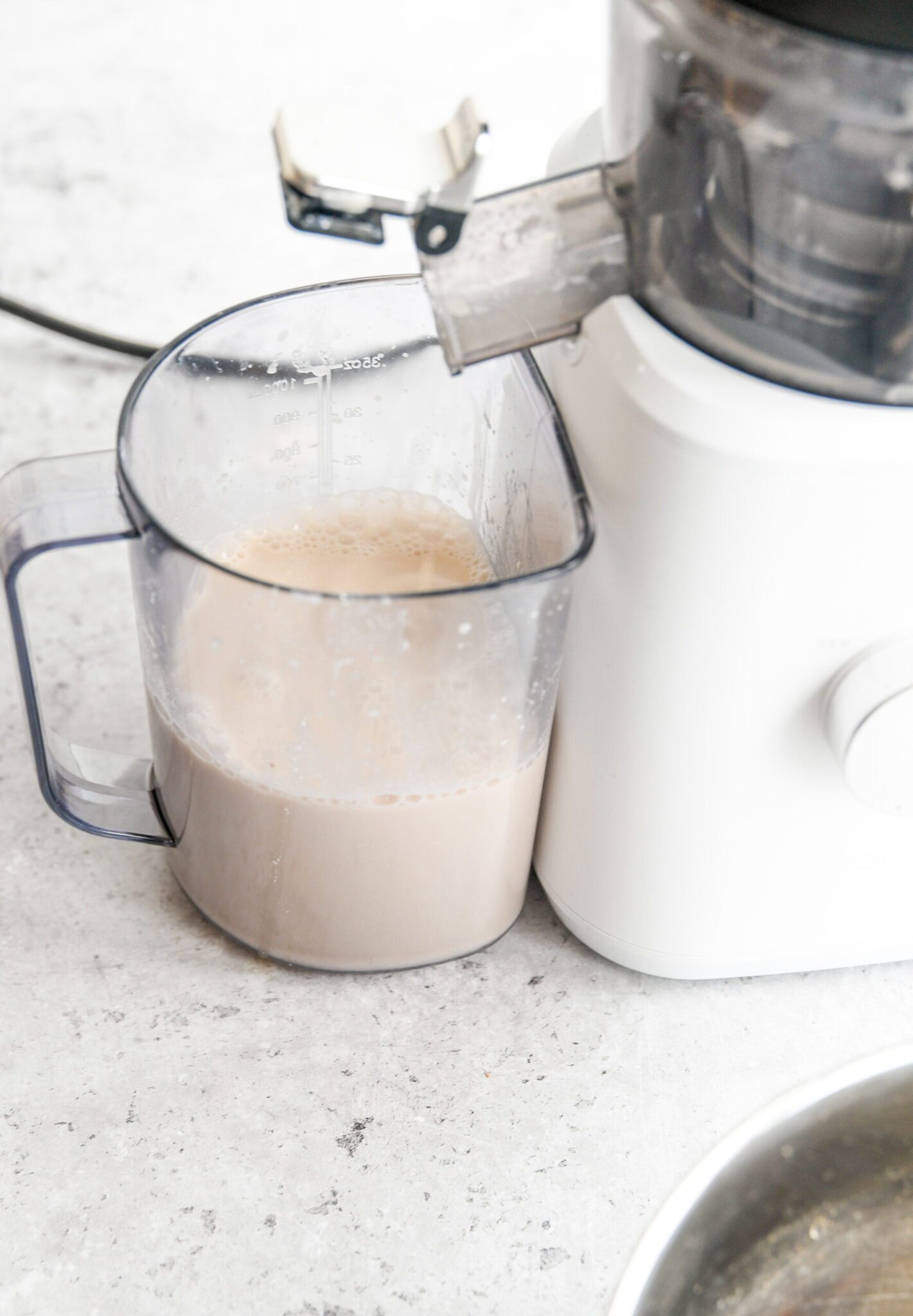 walnut milk in a plastic container next to a juicer