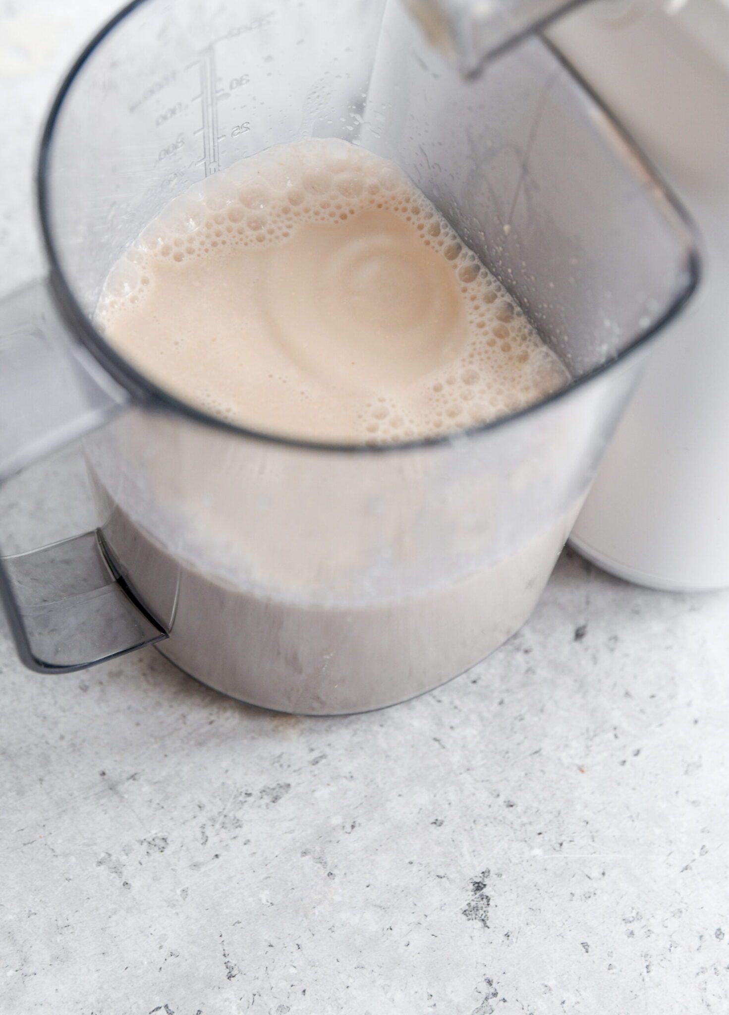 walnut milk in a plastic container next to a juicer
