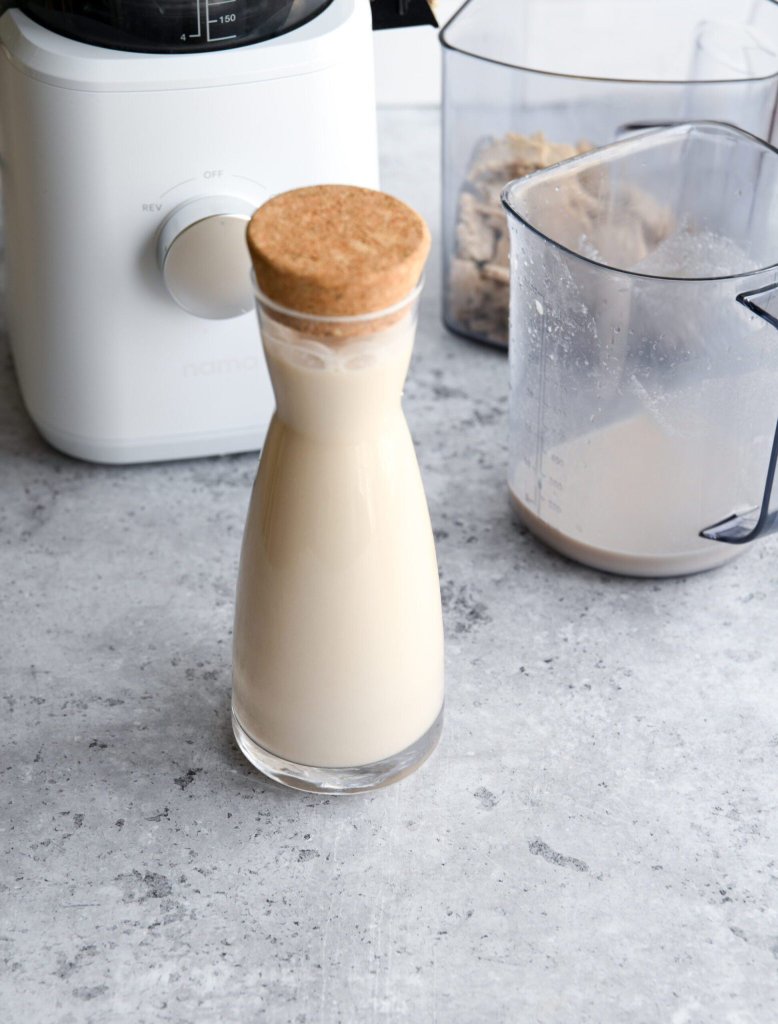 walnut milk in a glass bottle next to a juicer - how to make nut milk with a juicer