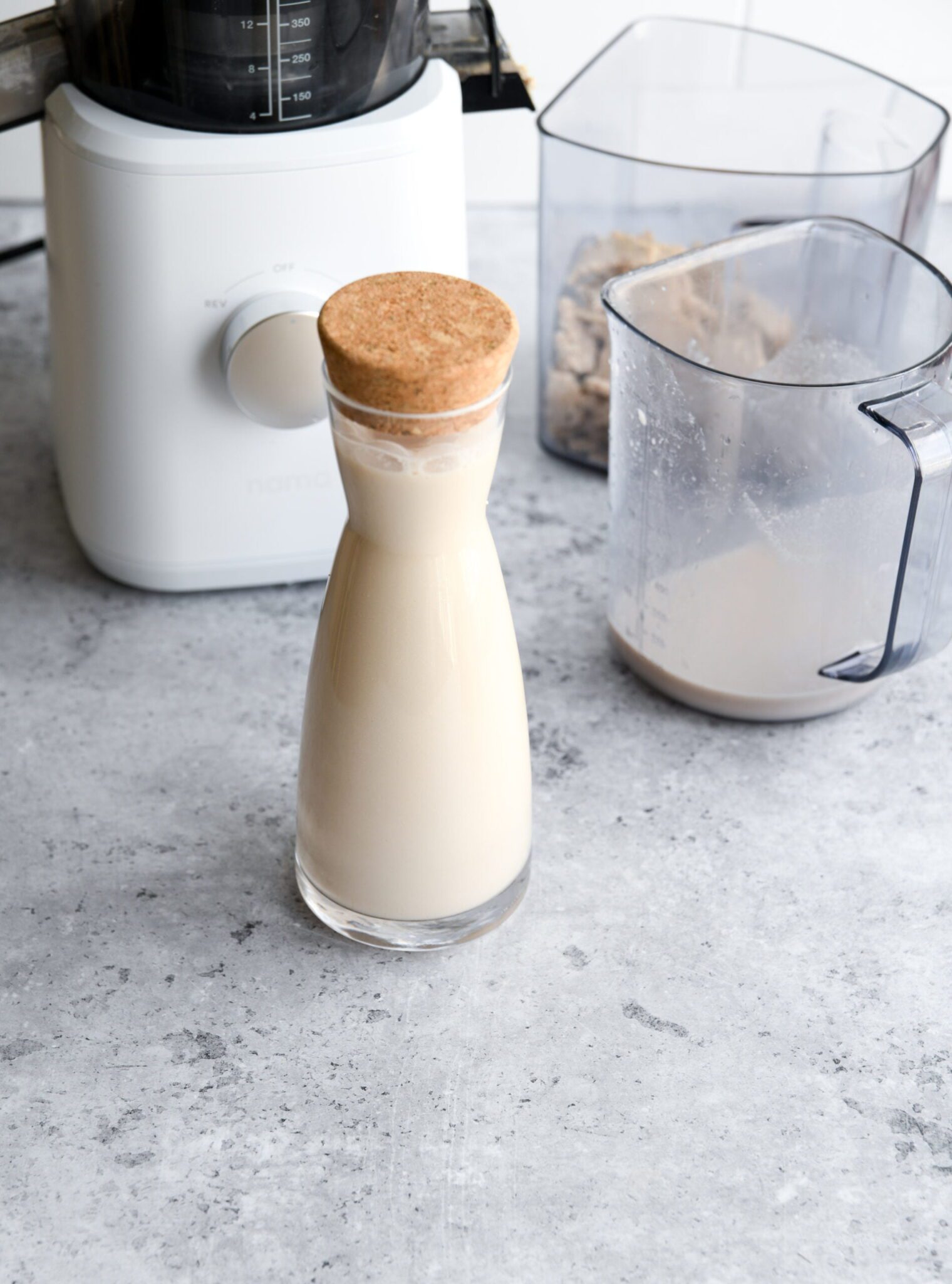 walnut milk in a glass bottle next to a juicer