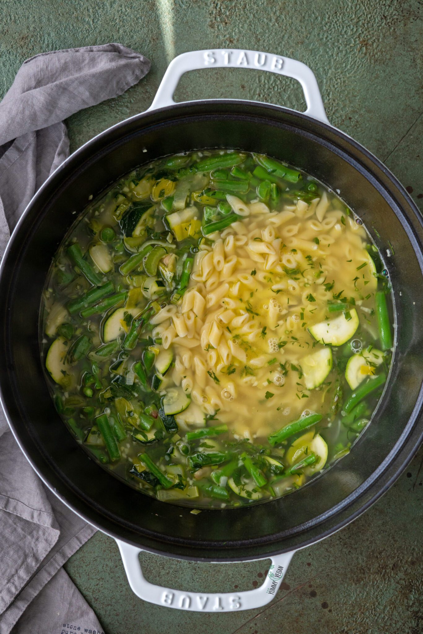 Green Minestrone Soup in a pot with noodles added