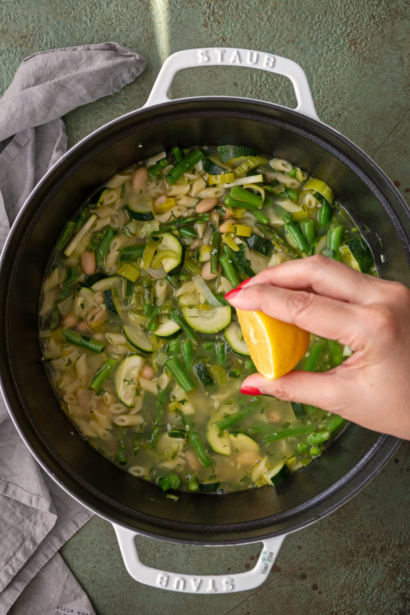 Green Minestrone Soup in a pot with lemon juice being squeezed in