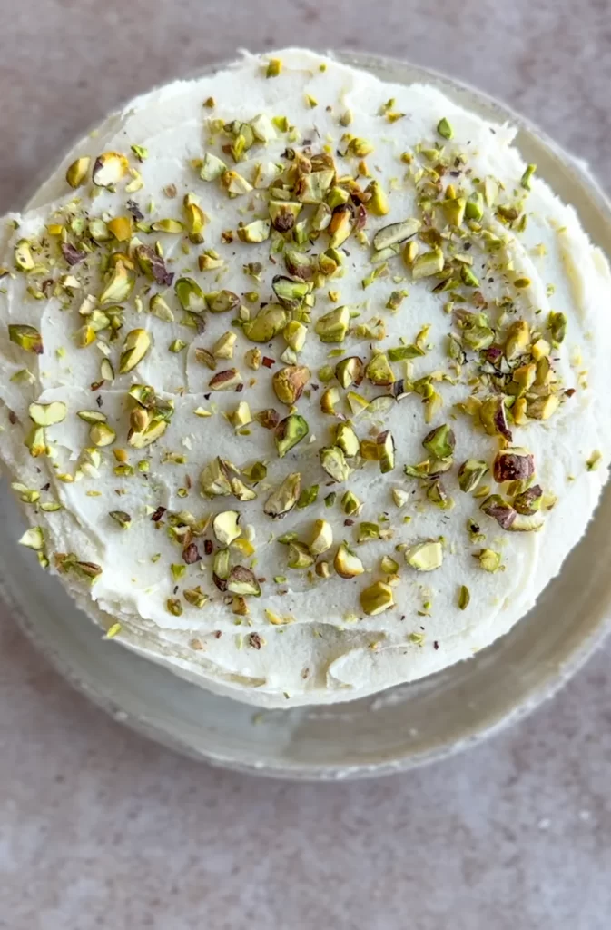 overhead view of a cake with frosting and chopped pistachios sprinkled on top