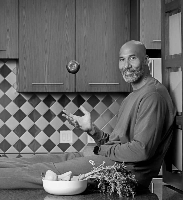 a man sitting on a kitchen floor with a bowl of fruit