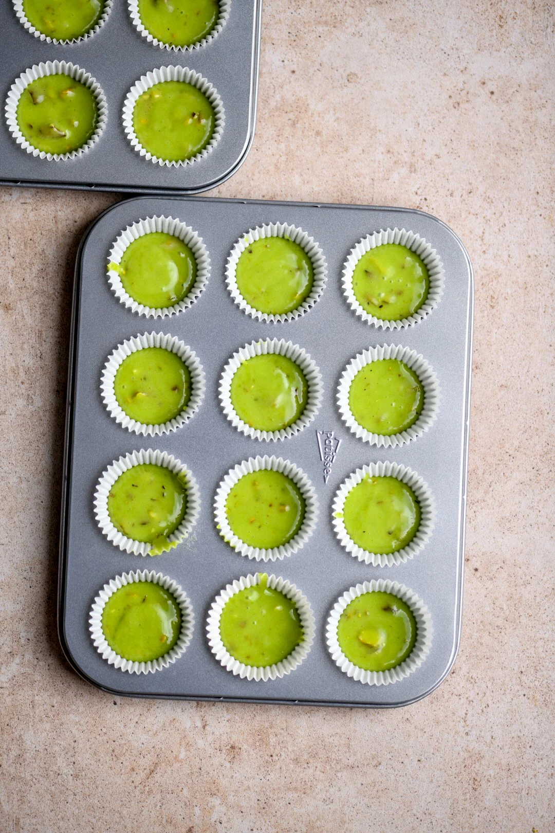 green pistachio cupcake batter in mini cupcake forms, half filled