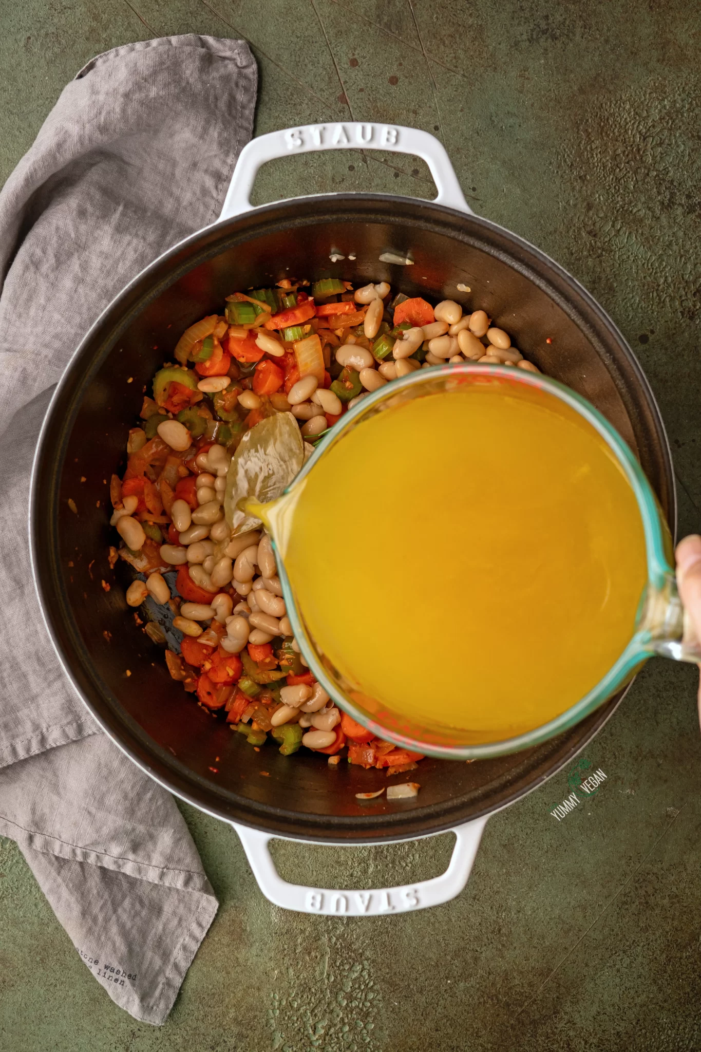 vegetable broth being added to a soup pot