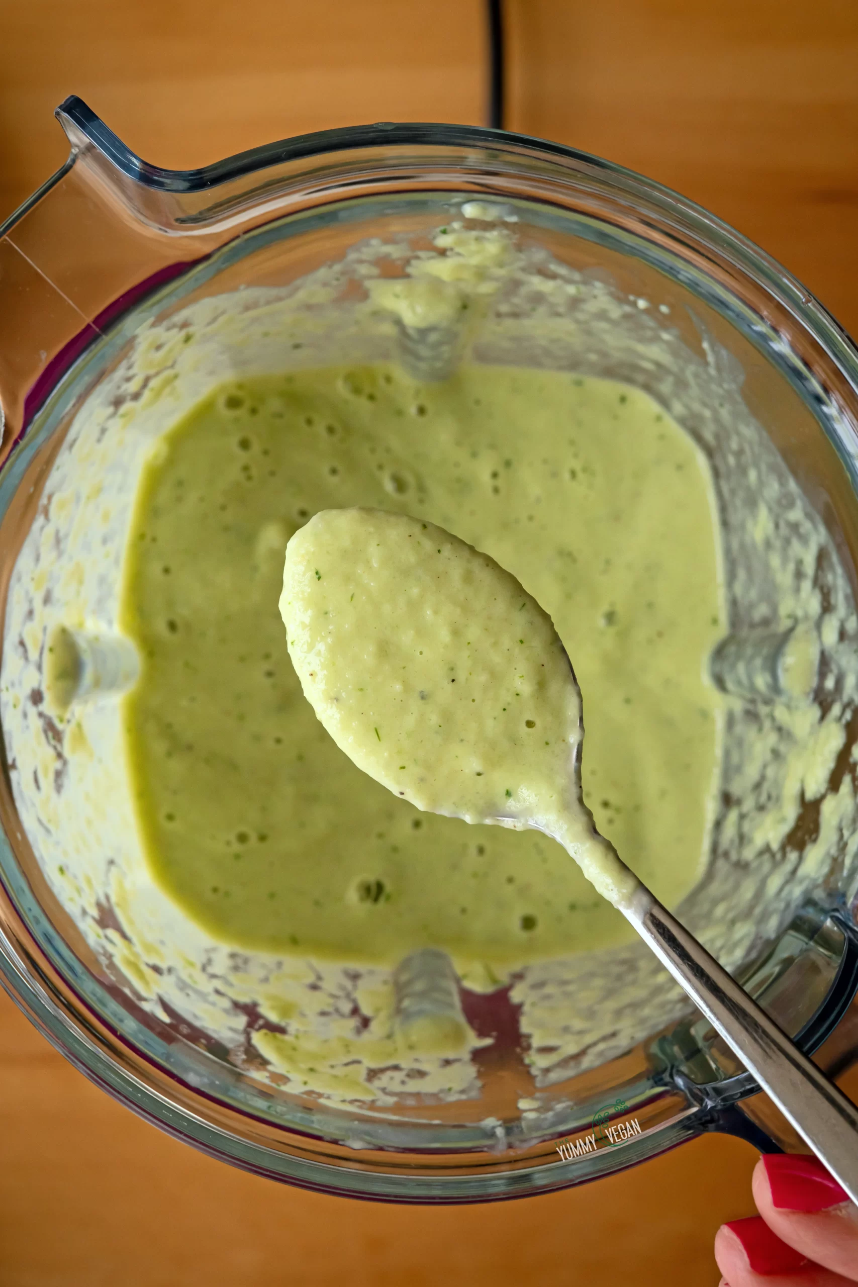 blended cold cucumber soup in a blender with a spoon scooping out a bit of the soup